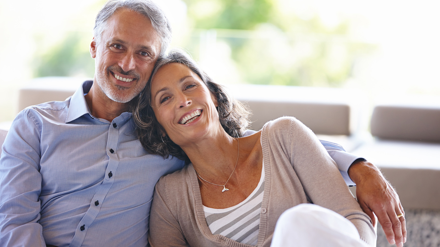 The image shows a man and woman sitting closely together, smiling at each other, with a warm and affectionate atmosphere, likely depicting a moment of shared happiness between them.