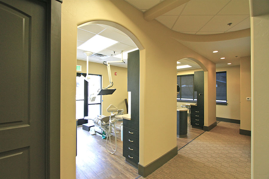 The image shows an interior view of a dental office with multiple chairs, cabinets, and dental equipment visible.