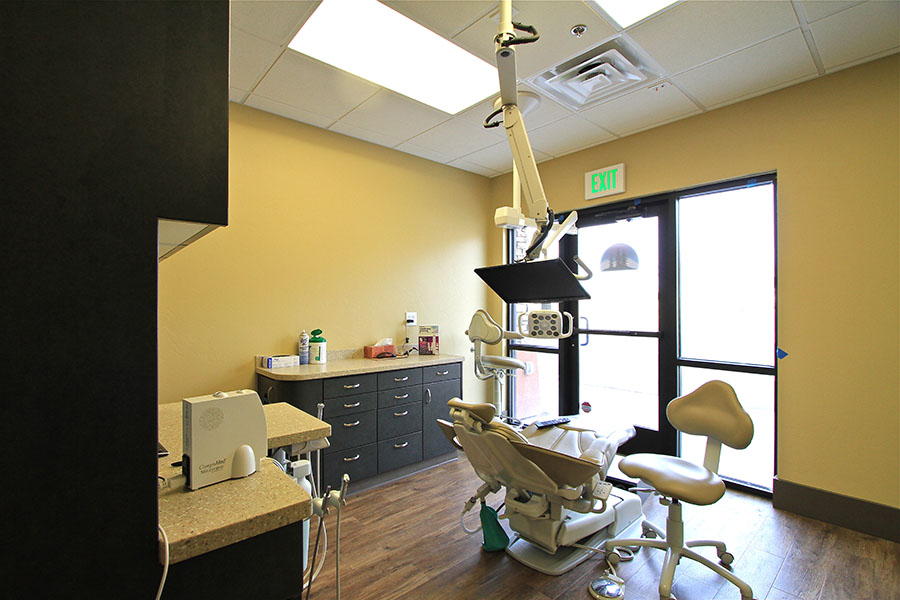 The image shows a dental office interior with various pieces of equipment and furniture, including a dentist's chair, dental instruments, and a reception desk.