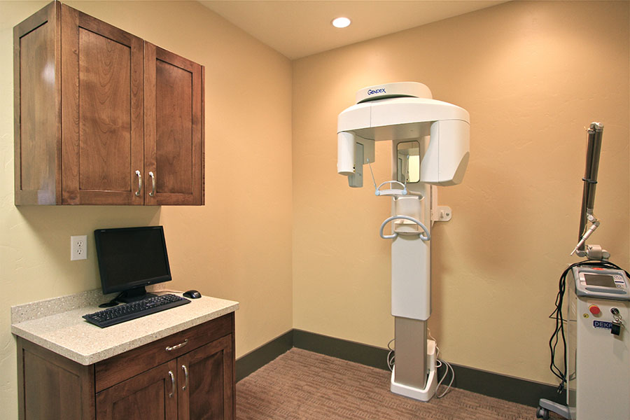 The image shows a dental office interior with a dental chair, a computer monitor, cabinets, and a countertop with a keyboard and mouse.