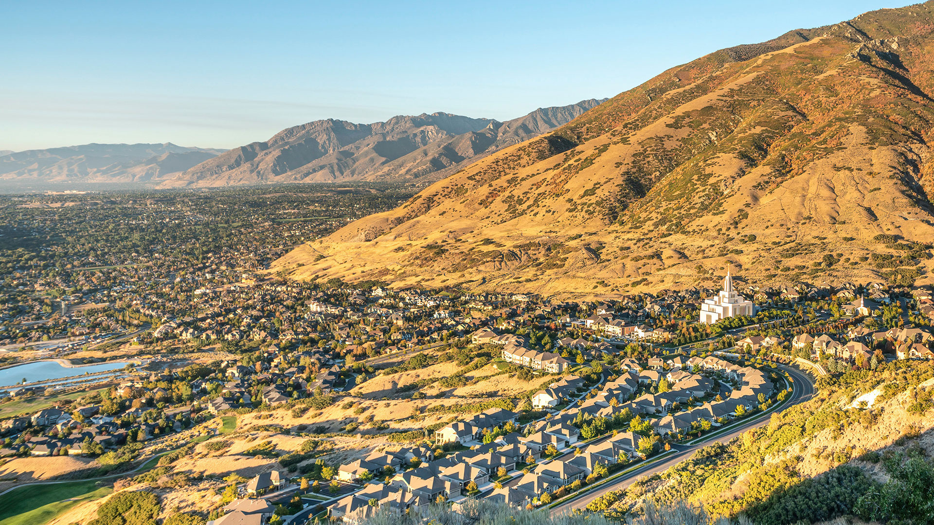 The image depicts a scenic mountainous landscape with a town nestled at its base under a clear sky.
