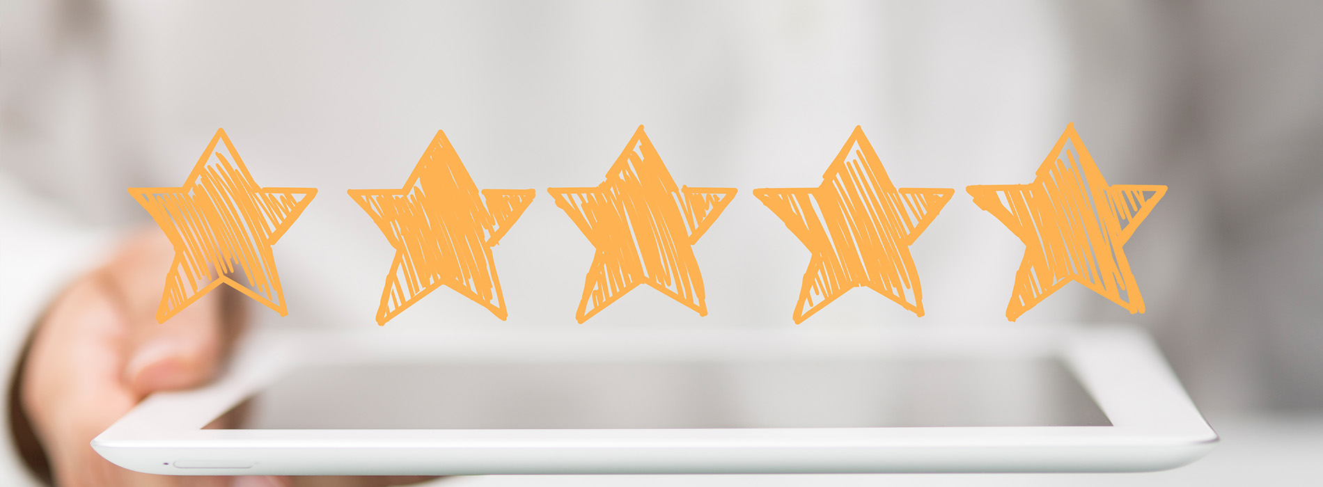 The image shows a tablet displaying multiple orange stars with a blurred background featuring a hand holding a tablet.