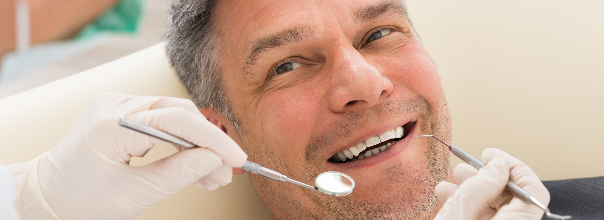 A man sitting in a dental chair with his mouth open while receiving dental care; he appears relaxed and content.