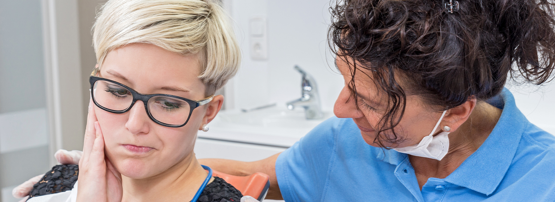 The image shows a dental hygienist assisting a patient during a dental appointment.