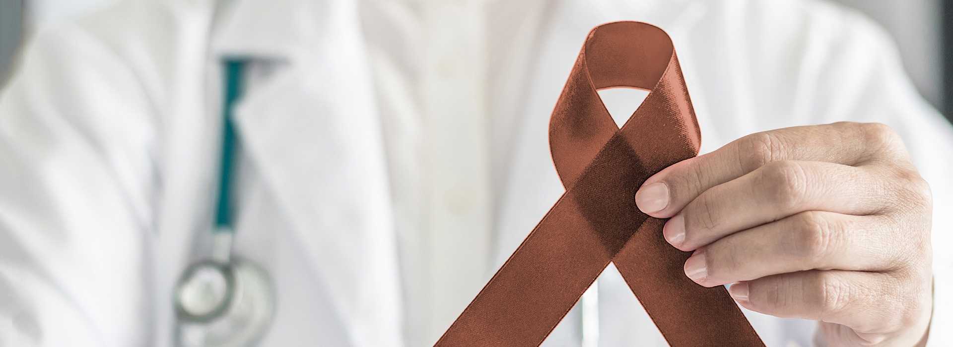 The image features a healthcare professional holding a red ribbon with a medical symbol on it, which is commonly associated with breast cancer awareness, against a background that includes a stethoscope and medical attire.