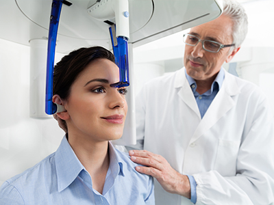 A woman wearing a blue headset receives a medical examination from a doctor in a professional setting.
