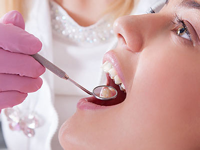 An individual receiving dental care with a dentist using tools on their teeth.