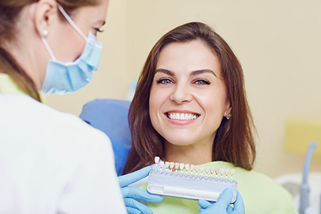 A woman receiving dental care, with a dental professional holding an instrument.