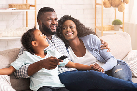 A family of four sitting on a couch, smiling and enjoying each other s company.