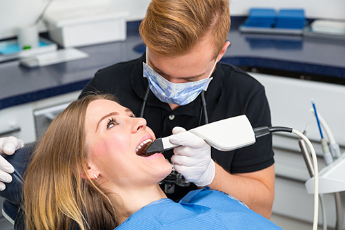 Woman receiving dental treatment with dental hygienist using an electric toothbrush.