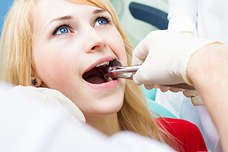 A young woman receiving dental treatment with a dentist s assistance.