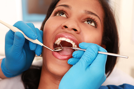 A dental hygienist performing oral care on a patient s teeth while the patient smiles.