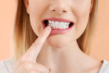The image shows a person with their finger placed on their teeth, seemingly about to bite into something.