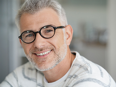 The image shows a man with glasses smiling at the camera, with a split-screen effect showing him from two different angles.