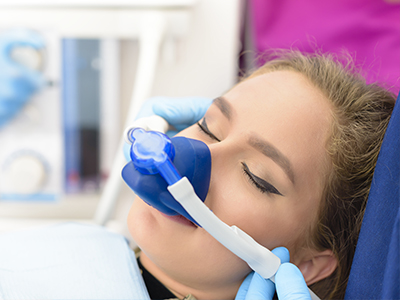 A woman receiving oxygen therapy with medical equipment in the background.