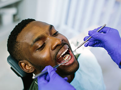 A man receiving dental treatment with a dental hygienist performing the procedure.